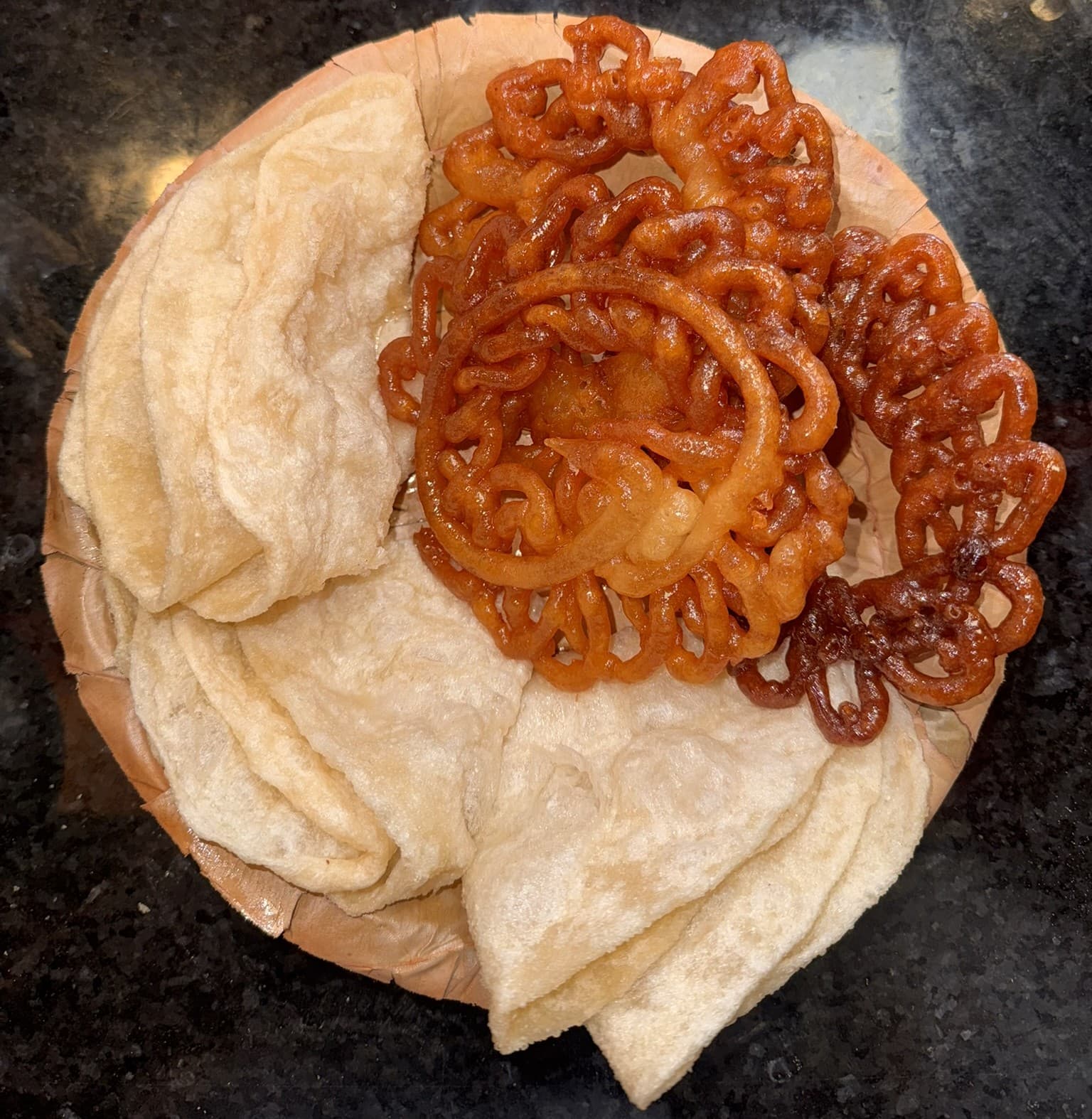 Jeri and swari on a leaf plate: syrup-soaked coils of jeri beside folded layers of swari