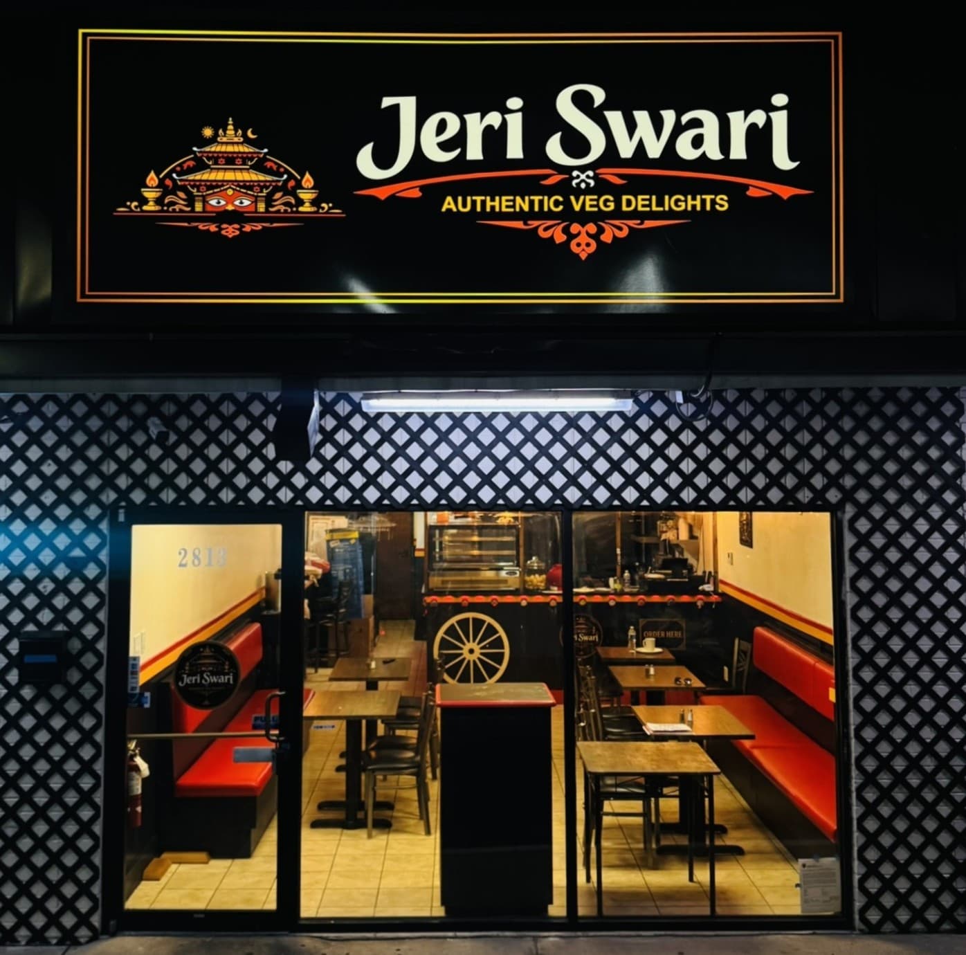 Jeri Swari's storefront at night, dining room lit behind the window
